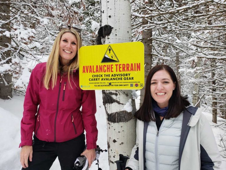 Women Snowshoeing & Avalanche Sign
